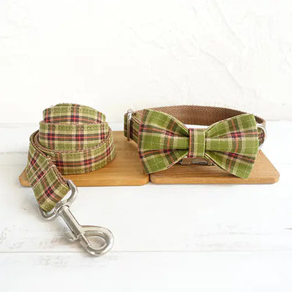 Green plaid dog collar with bow tie and leash on a wooden board
