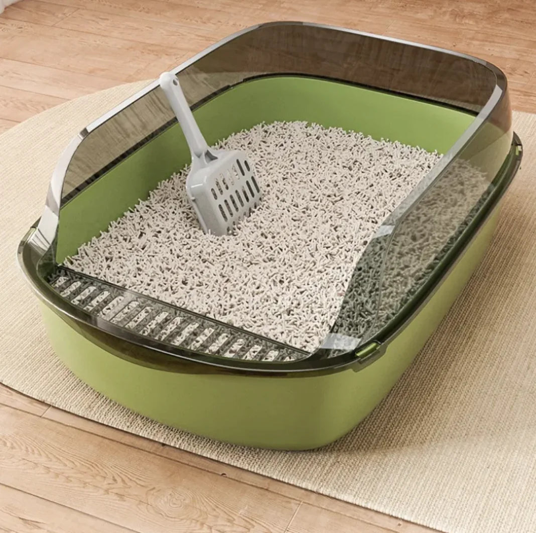 Green cat litter box with scoop on a wooden floor